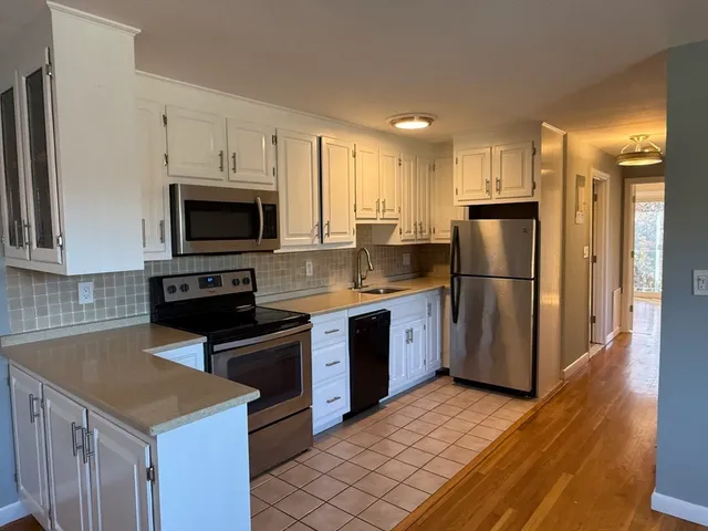 a kitchen with granite countertop a refrigerator a stove top oven a sink and dishwasher with wooden floor