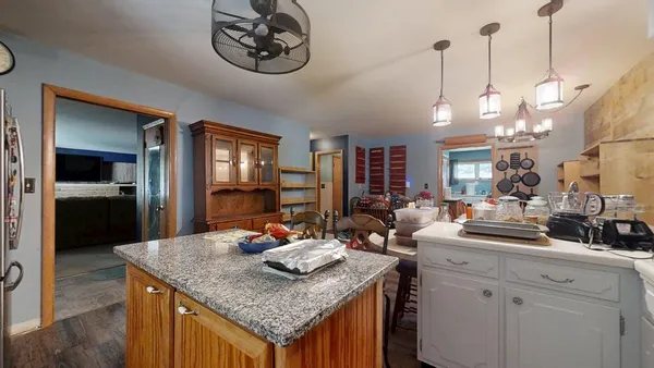 a view of a kitchen counter top space a sink wooden floor and a chandelier