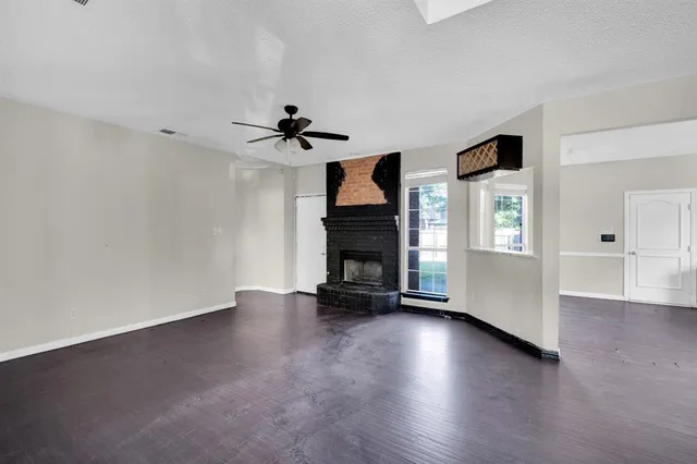 a view of an empty room with window fireplace and wooden floor