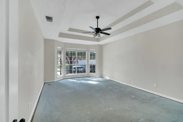 an empty room with windows and fan