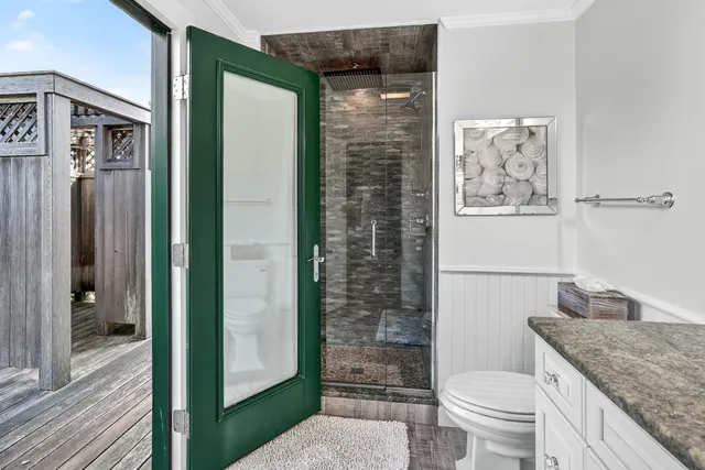 a bathroom with a granite countertop sink a toilet a shower and a mirror