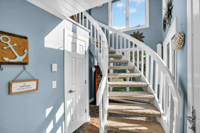 a view of staircase with lots of frames on wall and a window