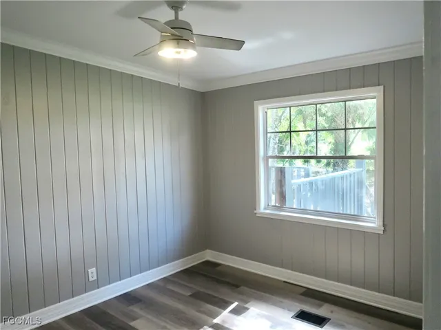 a view of empty room with wooden floor and fan