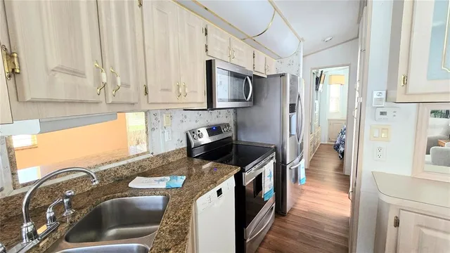 a kitchen with stainless steel appliances granite countertop a stove a sink dishwasher and cabinets with wooden floor