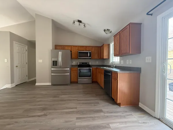 a kitchen with stainless steel appliances granite countertop a stove top oven a sink and dishwasher a refrigerator with wooden floor