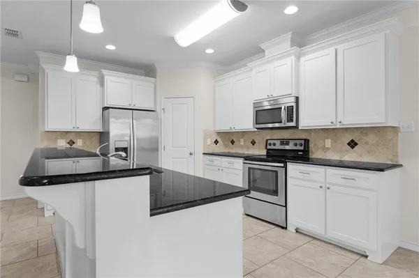 a kitchen with granite countertop a sink stainless steel appliances and white cabinets