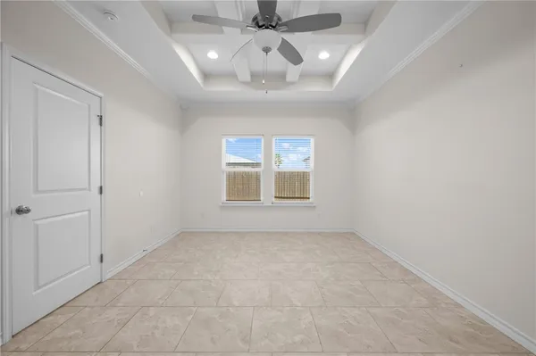 an empty room with a chandelier fan and windows
