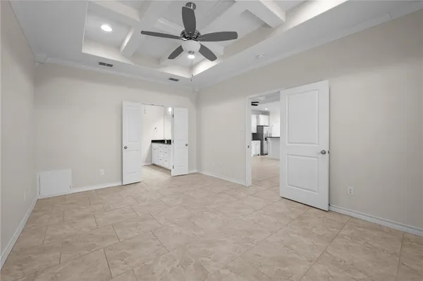 an empty room with an entryway and chandelier fan