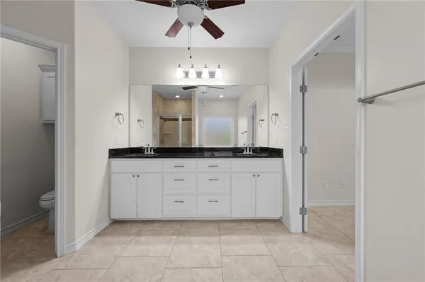 a spacious bathroom with a granite countertop sink a mirror and a shower