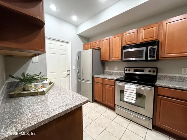 a kitchen with granite countertop wooden cabinets a stove top oven and stainless steel appliances