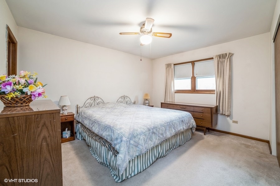 1208 Ridgeway Drive Elgin, IL 60123 - Photo 8 of 10 a spacious bedroom with a bed and a chandelier