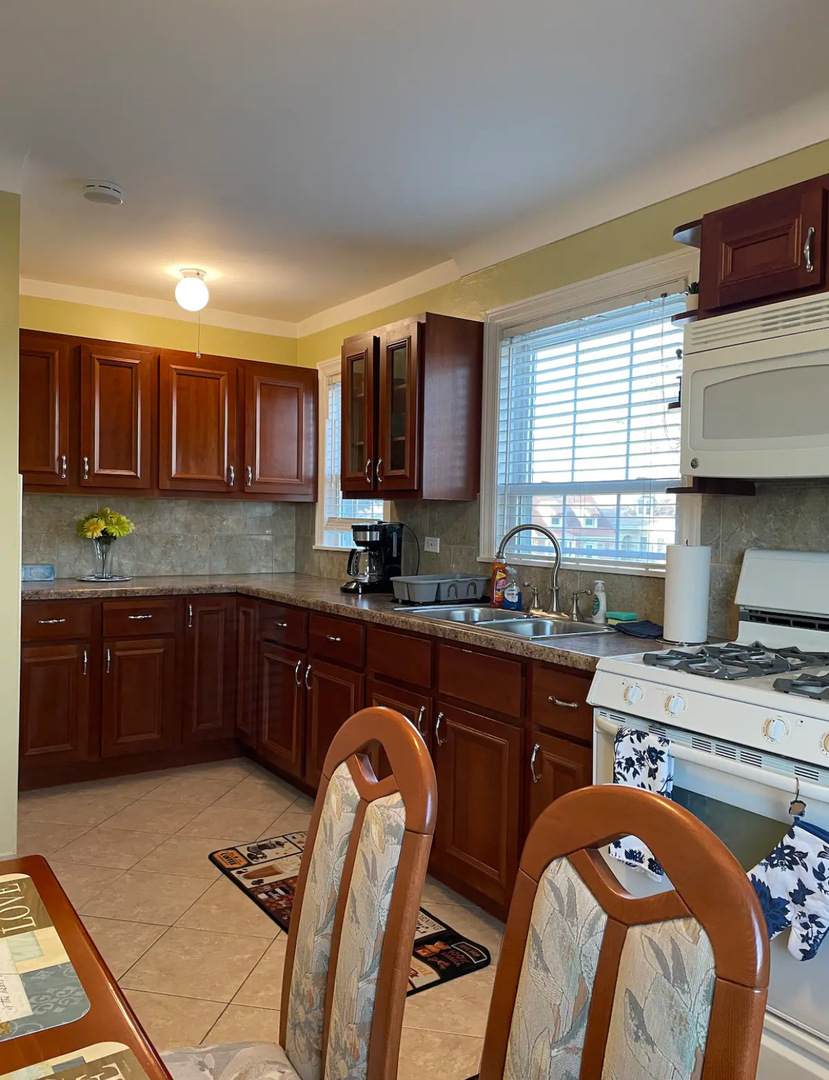 6101 West Fletcher Street, Unit 1 Chicago, IL 60634 - Photo 8 of 17 a kitchen with stainless steel appliances granite countertop a stove top oven a sink a dining table and chairs