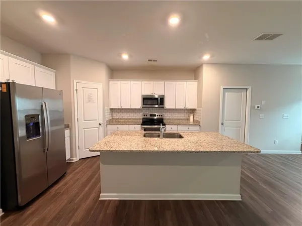 a large kitchen with kitchen island a sink wooden floor and stainless steel appliances