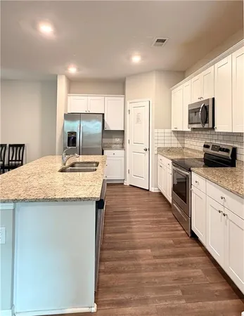 a kitchen with stainless steel appliances granite countertop a kitchen island hardwood floor sink stove and granite counter top