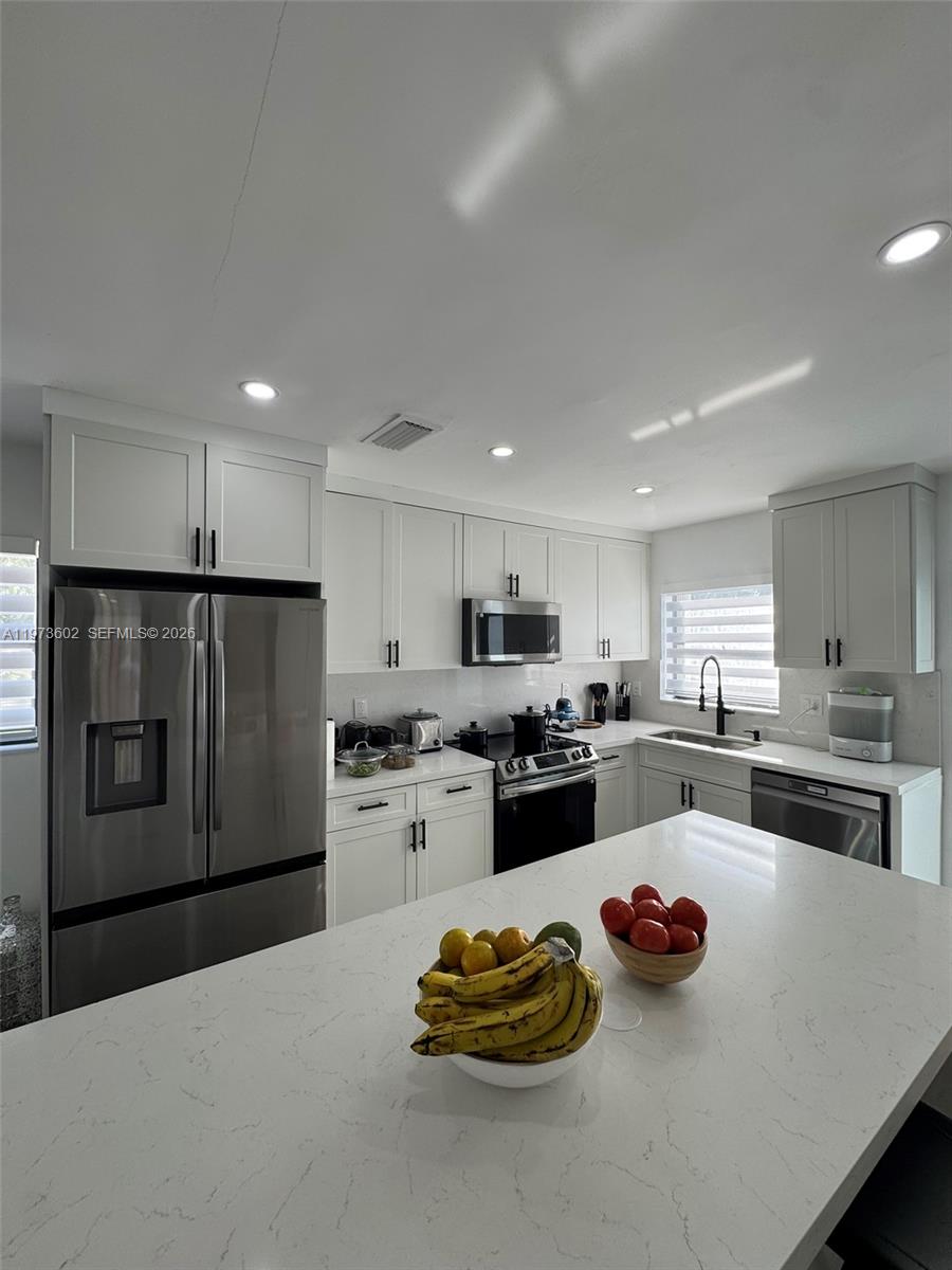 12534 Southwest 27th Street Miami, FL 33175 - Photo 13 of 49 a kitchen with a refrigerator a stove a sink dishwasher and white cabinets with wooden floor
