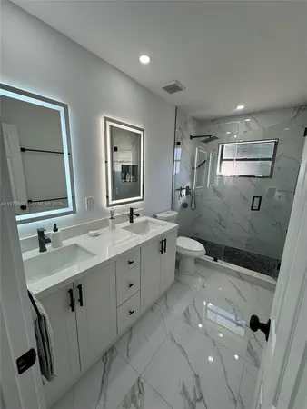 a bathroom with a double vanity sink mirror and toilet