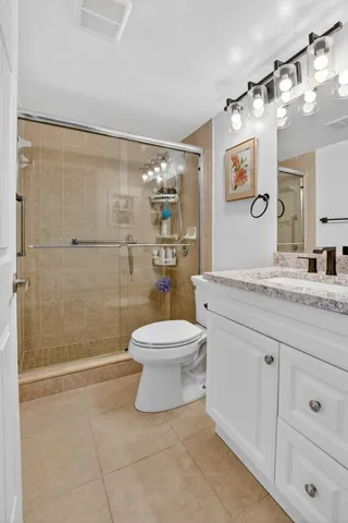 a bathroom with a granite countertop toilet a sink a mirror and shower