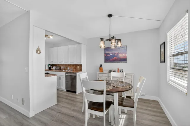 a view of a dining room and livingroom with furniture wooden floor a chandelier