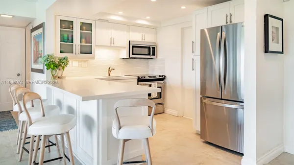 a kitchen with stainless steel appliances a refrigerator a stove a dining table and chairs