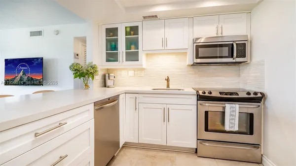 a kitchen with stainless steel appliances white cabinets and stove top oven