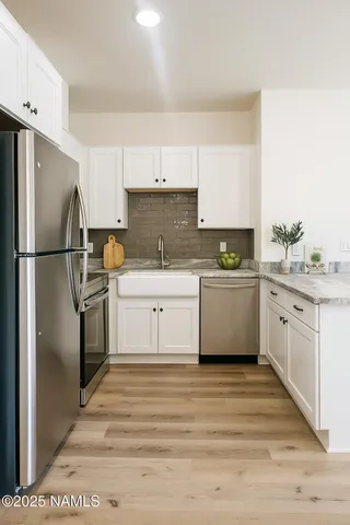a kitchen with a white cabinets white stainless steel appliances and a refrigerator