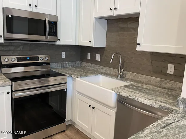 a kitchen with stainless steel appliances granite countertop a stove microwave and sink