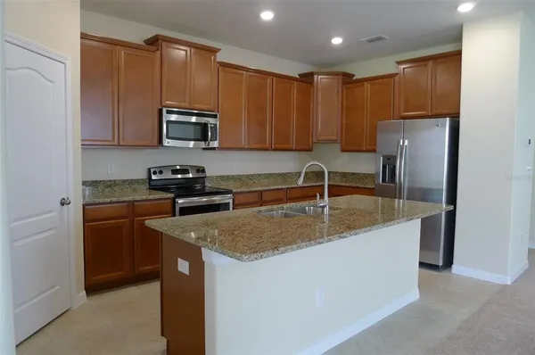 a kitchen with stainless steel appliances granite countertop a sink a stove and a refrigerator