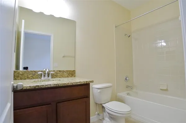 a bathroom with a granite countertop sink toilet mirror and shower