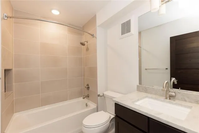 a bathroom with a granite countertop bathtub shower sink vanity mirror and toilet