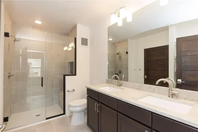 a bathroom with a double vanity sink toilet and shower