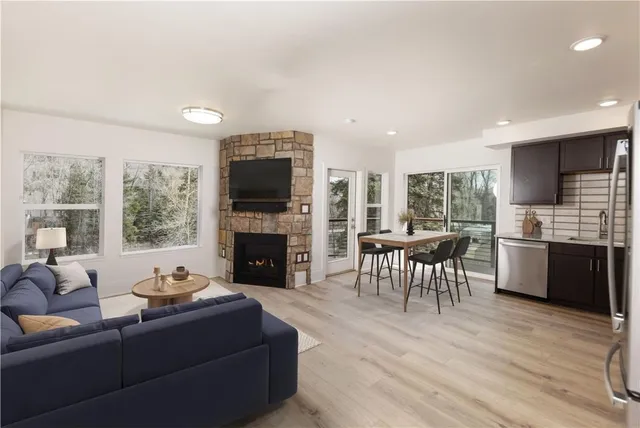 a living room with furniture a fireplace a flat screen tv and a large window
