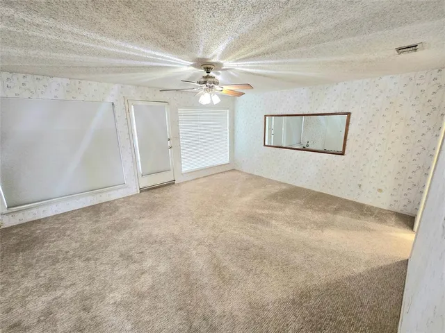 an empty room with windows and fan