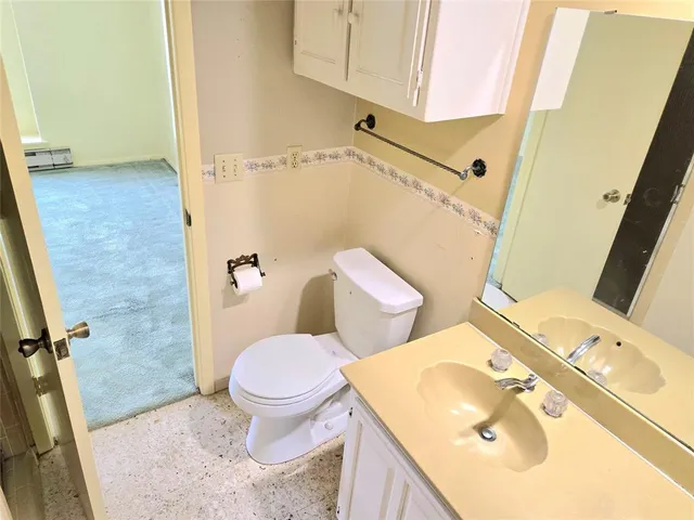 a white toilet sitting next to a bathroom sink and a mirror
