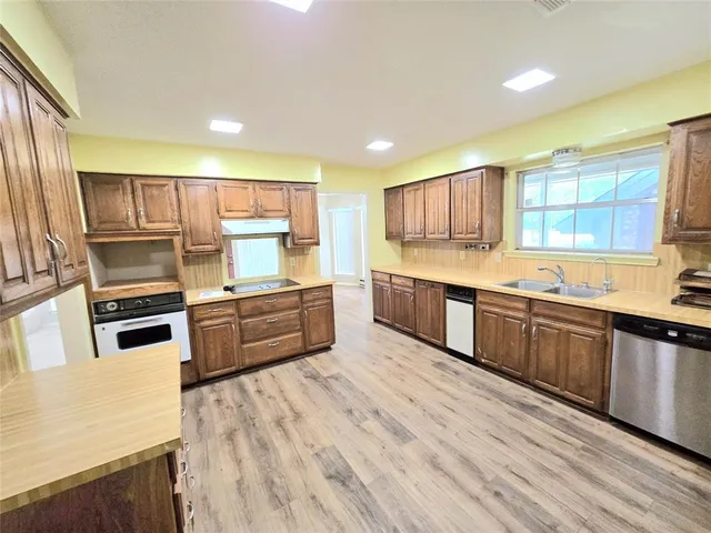 a large kitchen with a large counter top a sink stainless steel appliances and cabinets