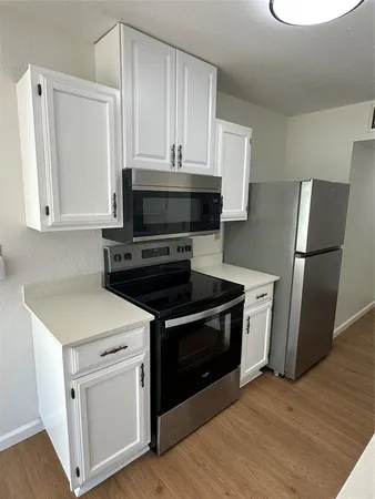 a kitchen with white cabinets and stainless steel appliances