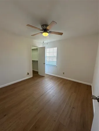 a view of an empty room with window and wooden floor