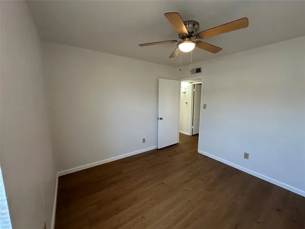 an empty room with wooden floor and ceiling fan
