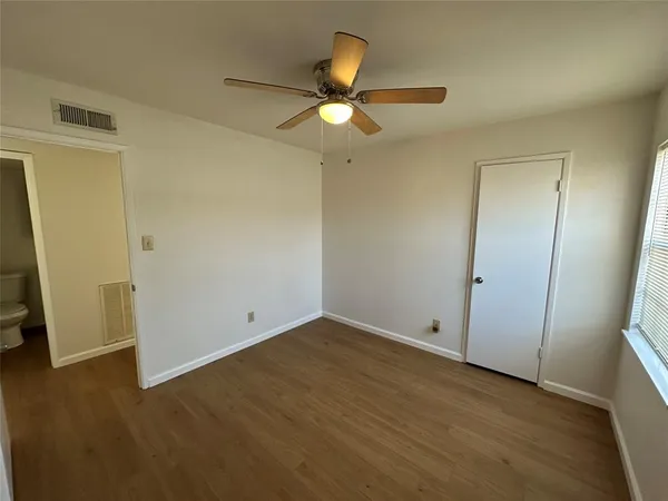 an empty room with wooden floor and a ceiling fan