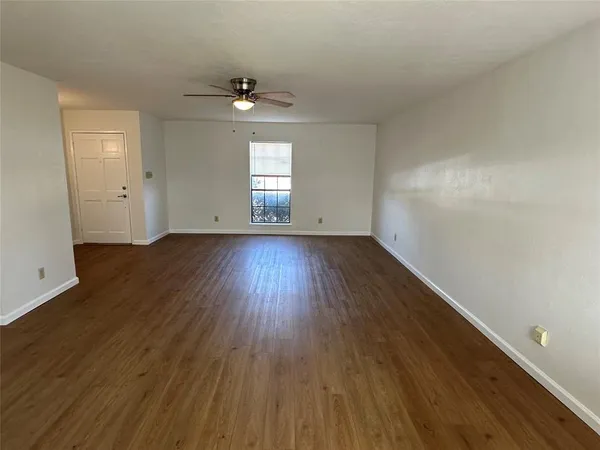 an empty room with wooden floor chandelier and windows