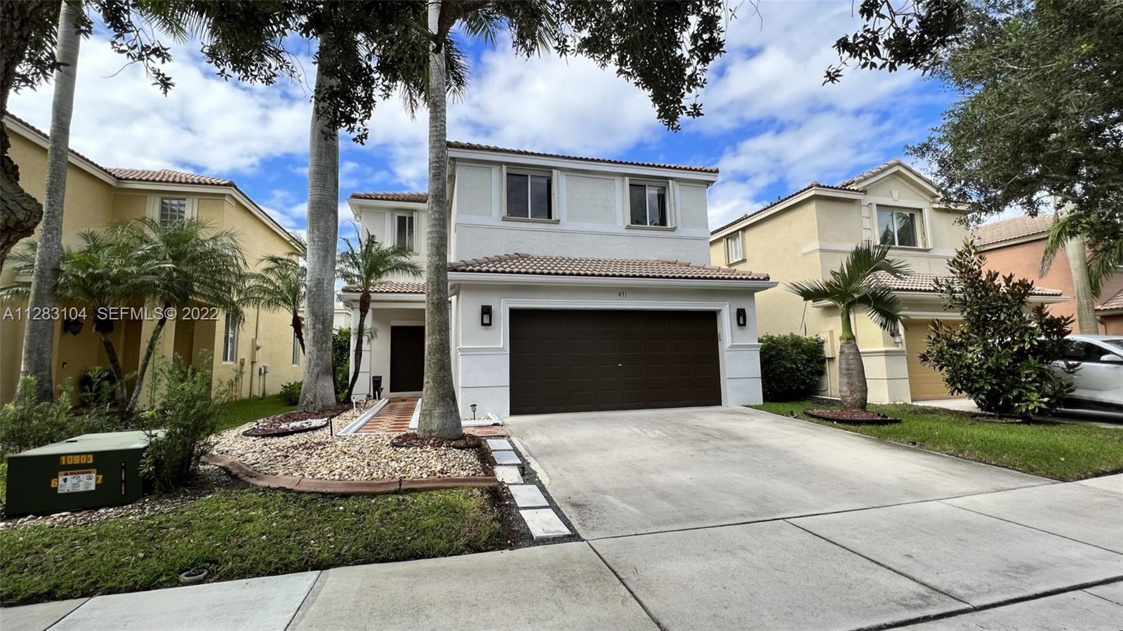 a front view of a house with a garden and trees