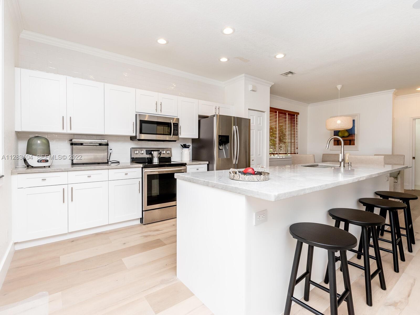 471 Fishtail Terrace Weston, FL 33327 - Photo 9 of 64 a kitchen with kitchen island white cabinets and appliances