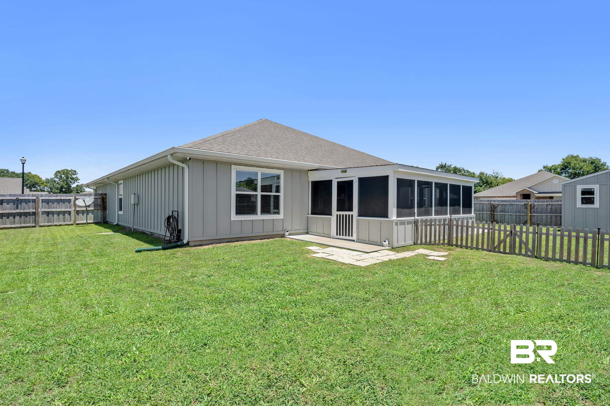 24271 Ringneck Loop Elberta, AL 36530 - Photo 42 of 44 Rear exterior featuring a screened porch, light grey vertical siding, a wood privacy fence, a picket fence, and a detached shed