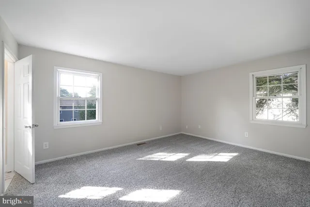 an empty room with wooden floor a fireplace and windows