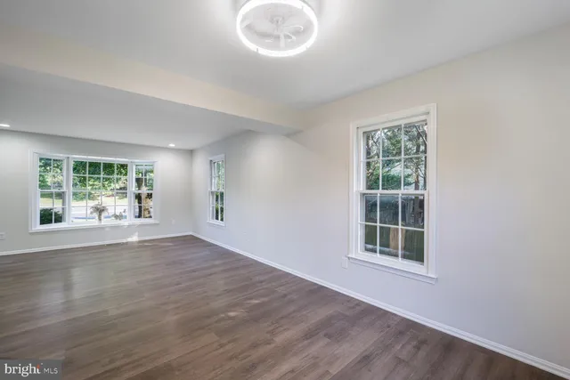 a view of empty room with wooden floor and windows