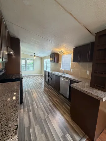 a kitchen with granite countertop a sink a counter space stainless steel appliances and cabinets
