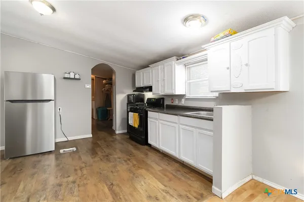 a kitchen with granite countertop a refrigerator and a stove top oven