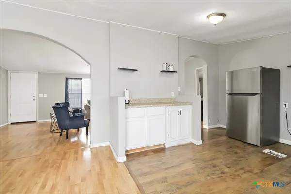 a view of a kitchen with refrigerator and wooden floor