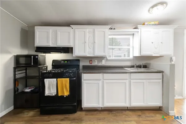 a kitchen with granite countertop white cabinets and black appliances