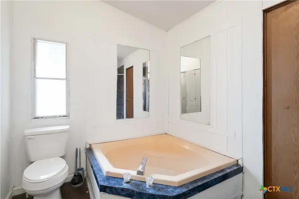 a room with a toilet a sink and mirror