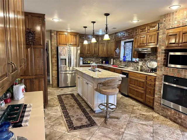 a kitchen with stainless steel appliances kitchen island granite countertop a sink and a refrigerator
